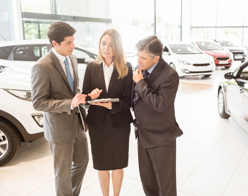 Car salespeople in conversation on dealership floor